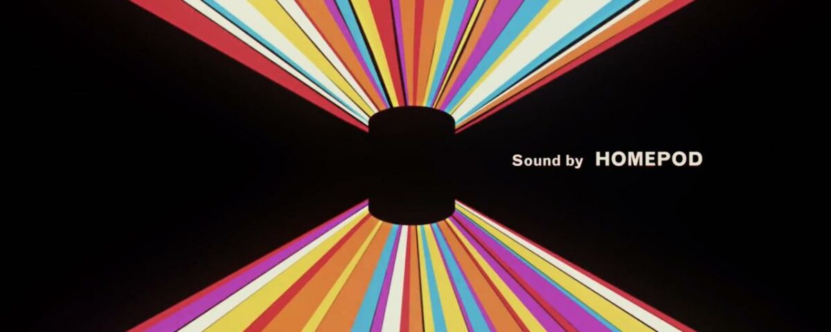 Una imagen tomada del video introductorio de Apple para HomePod, que muestra el parlante inteligente contra un fondo negro con rayas de luz de colores y el lema "Sonido de HomePod".
