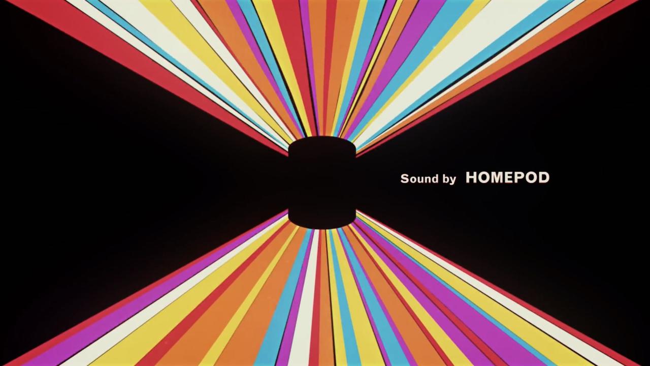 Una imagen tomada del video introductorio de Apple para HomePod, que muestra el parlante inteligente contra un fondo negro con rayas de luz de colores y el lema "Sonido de HomePod".