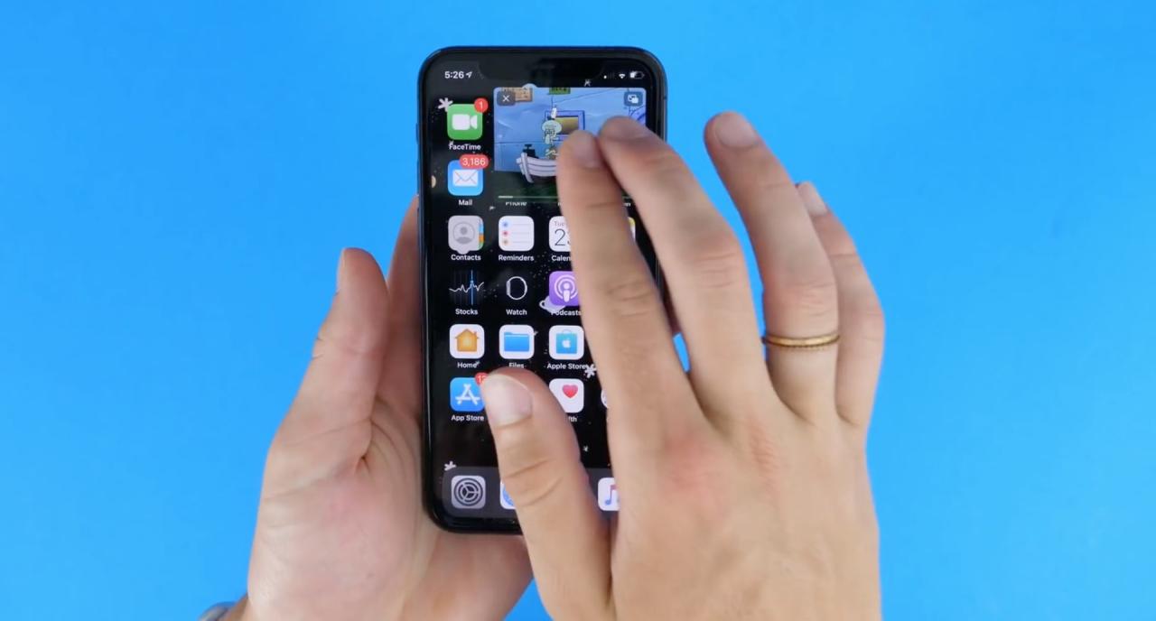 Una imagen fija que muestra un iPhone sostenido en la mano con un video reproduciéndose en modo PiP en la pantalla de inicio
