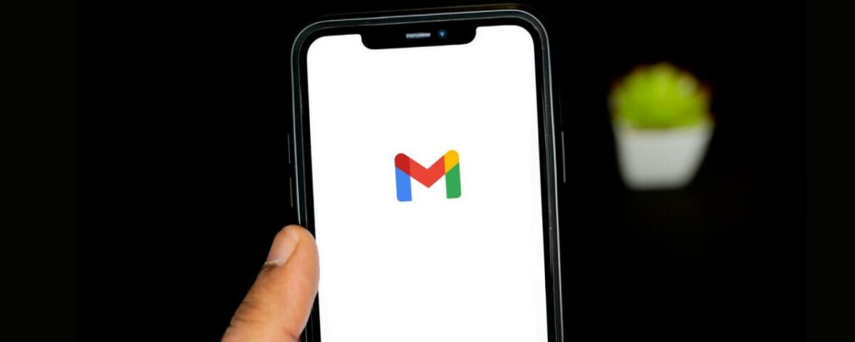 Una mano sujetando un iPhone con el logo de Gmail en la pantalla