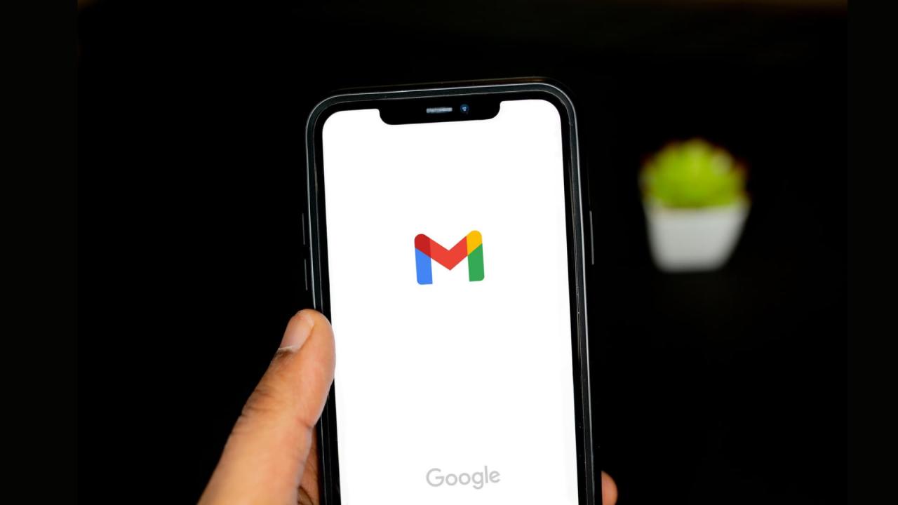 Una mano sujetando un iPhone con el logo de Gmail en la pantalla