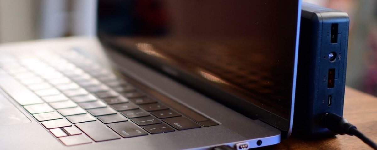 Una MacBook Pro con la tapa abierta y un banco de energía conectado a su puerto USB-C