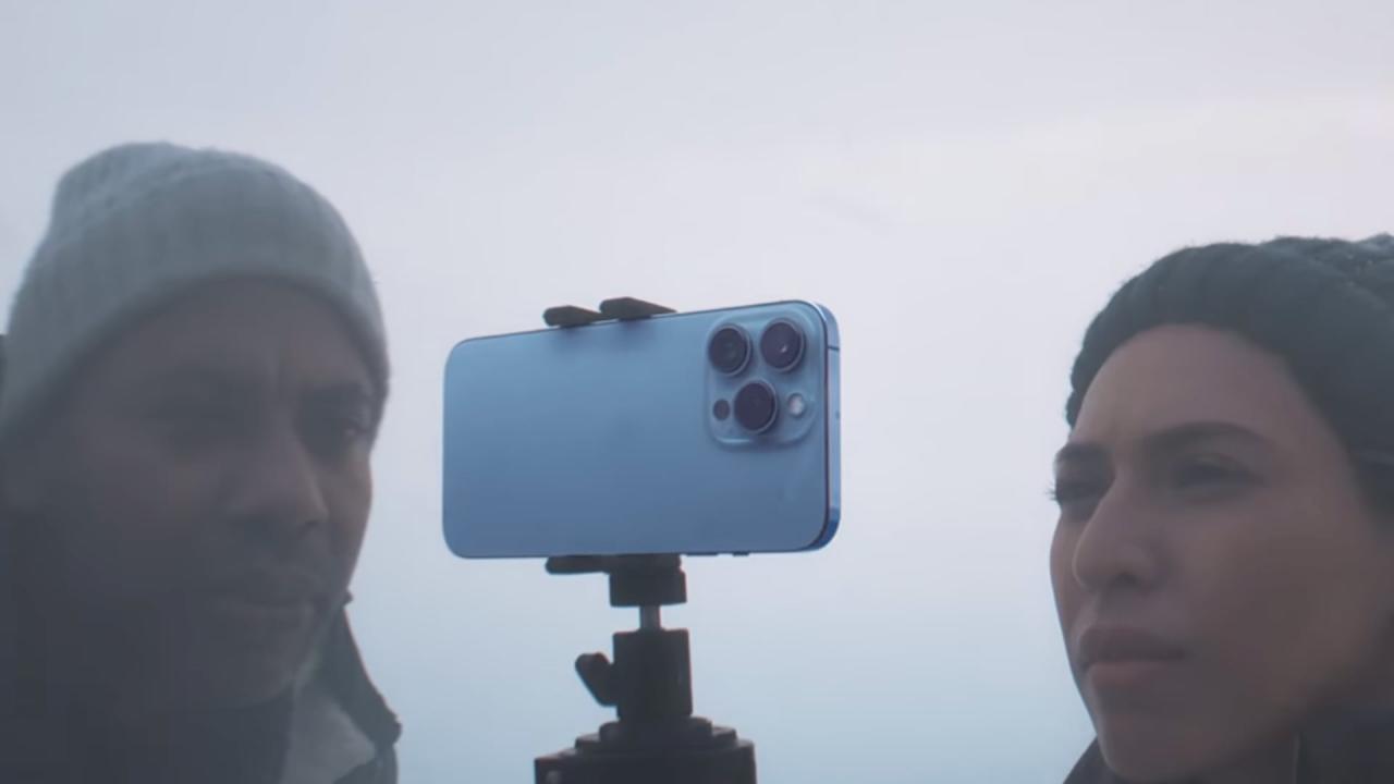 Una imagen fija tomada del video de presentación del iPhone 13 Pro de Apple en YouTube, que muestra un primer plano de dos miembros del equipo filmando una escena de invierno usando un trípode para el teléfono.