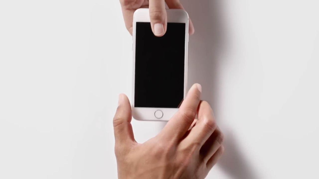 scene from Ap-in ad showing a male hand handing an iPhone 5s over to another male's hand