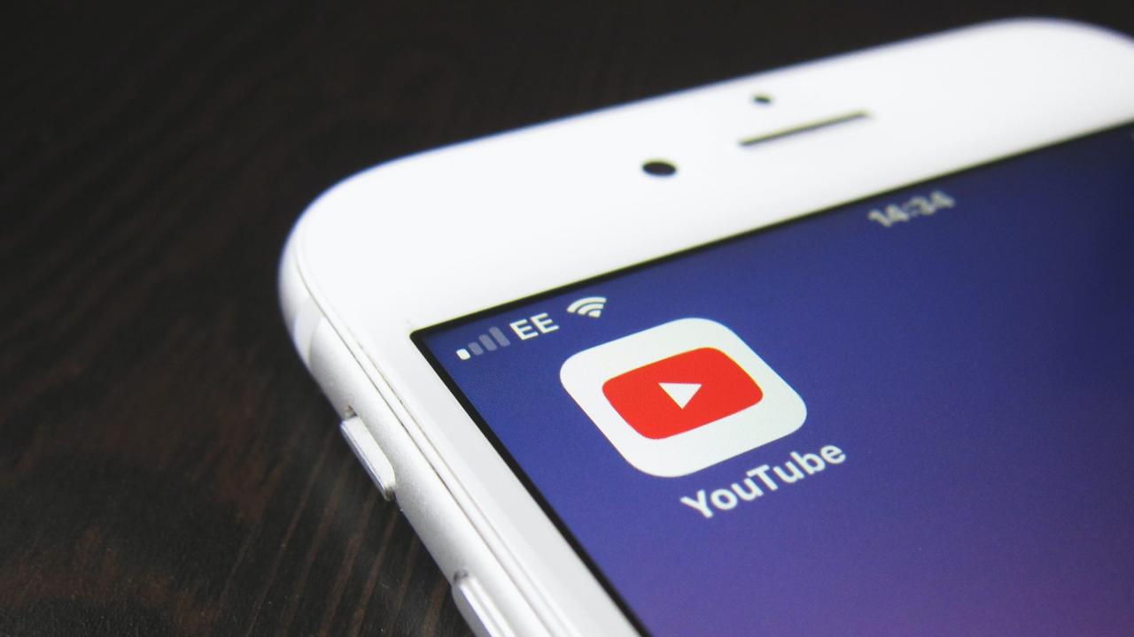 Una fotografía de primer plano de un iPhone blanco con un ícono para la aplicación Google YouTube que se muestra en la pantalla de inicio