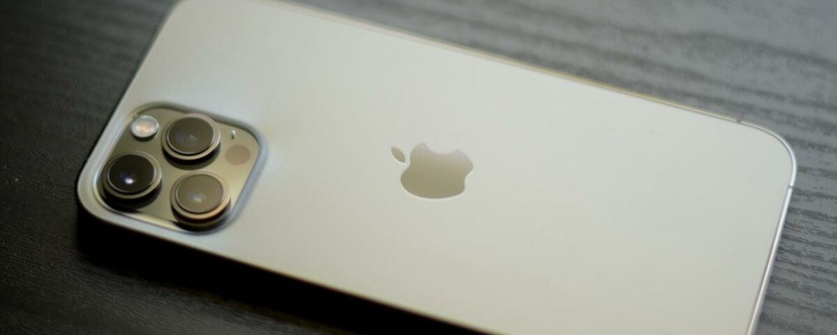 Un iPhone 12 Pro Max dorado colocado boca abajo sobre una mesa de madera